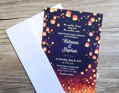 the wedding card is on top of an envelope and it has lanterns floating in the air