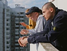 two men sitting on a ledge looking at something