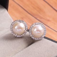 This Sterling Silver Earring features an Elegant Art With Natural Pearl Gemstone surrounded by tiny Zircon Gemstones. The cavity is made from genuine solid 925/92.5 Sterling silver and stamped as S925. This Jewelry is Lead free and finished with Rhodium to resist scratches and tarnish. ITEM DESCRIPTION Item Code: JAER278/21 Metal: 925/92.5 Sterling Silver Gemstone: Natural Pearl Gemstone Shape: Round Gemstone Size: 9 x 9 MM Surrounded Stones: Zircon Earring Length: 12 MM Earring width: 12 MM Wei Classic Gemstone Clip-on Earrings For Anniversary, Sterling Silver Round Earrings With Halo Setting, Diamond White Earrings With Halo Setting For Gift, Elegant Round Gemstone Cluster Earrings, White Pearl Earrings In Sterling Silver, Sterling Silver White Gold Matching Pearl Earrings, White Sterling Silver Earrings With Halo Design, Cubic Zirconia Halo Setting Earrings As Gift, Halo Setting Cubic Zirconia Earrings As Gift