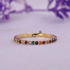 a yellow gold ring with multicolored stones on the inside, and an inscription above it