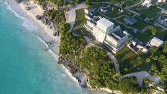 an aerial view of a beach with houses on the shore and trees in the foreground