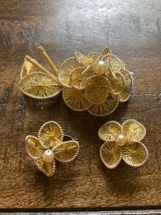 three pieces of gold filigrees with pearls on them sitting on a wooden table