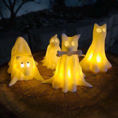 some white lights that are on top of a tree stump in the dark with cats and ghost faces