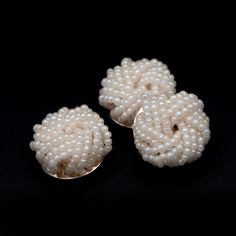 three pieces of white pearls are sitting on a black surface