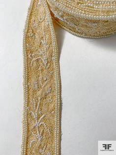 a close up of a ribbon on a white surface with pearls and beads around it