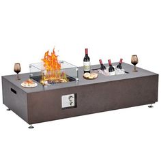 an outdoor fire pit with wine glasses and bottles on the top, in front of it