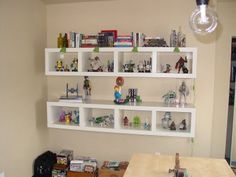 a room with shelves filled with toys and other items on the wall above a table