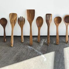 six wooden spoons lined up in a row on the floor next to each other