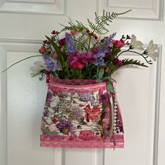 a pink purse with flowers in it hanging on a door handle and lace around the bottom