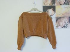 a brown sweater hanging on a white wall next to pictures and a hanger with two photos