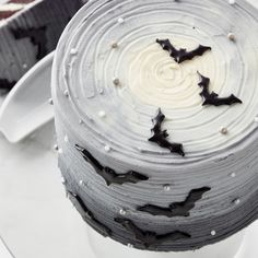 two cakes with white frosting and black bats on them, one is half eaten