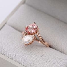 an engagement ring with two pear shaped pink stones in the middle and one pear shaped white stone