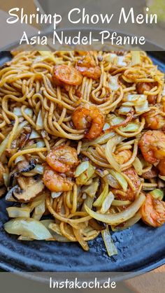 shrimp chow mein with noodles and vegetables on a blue plate in front of a wooden table