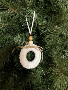 an ornament hanging from a christmas tree on a string with wood bead