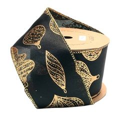 a roll of black and gold foiled ribbon with leaves on it, sitting on top of a wooden stand