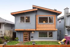 a blue house with wood trim and windows on the front, in a residential neighborhood