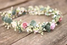 a flower crown is sitting on a wooden table with white and pink flowers in it