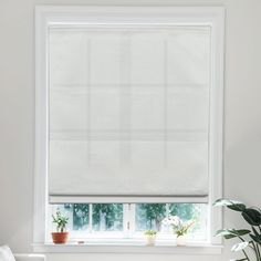 a living room with white walls and a large window covered in blinds that are covering the windows