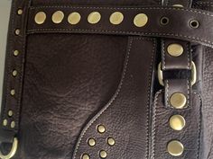 "Guys, you need this stylish shoulder bag for essentials, like your notebook or mini laptop devices, your phone, journal, wallet and keys. And, ladies, you already know how beneficial crossbody handbags are and this one is hard-core, smokin' biker bad. Oversized brass nailhead studs and an edgy geometric design make this an artistic statement that'll enhance even a basic, solid color t-shirt. Functional and secure, this hip bag features 2 exterior zipper compartments, 1 interior zipper compartme Designer Satchel With Mobile Phone Bag For Travel, Designer Satchel With Mobile Phone Bag For Everyday, Designer Leather Satchel With Mobile Phone Bag, Modern Travel Bags With Hardware, Rectangular Satchel With Hardware For Daily Use, Designer Travel Bags With Cell Phone Pocket, Leather Tote Shoulder Bag With Hardware, Leather Travel Satchel With Hardware, Daily Use Satchel Shoulder Bag With Hardware