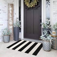 the front door is decorated with potted succulents and a welcome mat