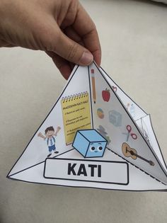 someone is holding up a paper kite with an image of a cube on it and the word kati