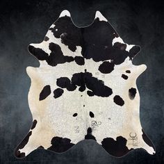 a black and white spotted cowhide rug on a dark background with the word love written in cursive writing