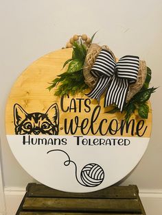 a wooden sign with a cat's welcome and yarn ball on the bottom that says, cats welcome humans televated