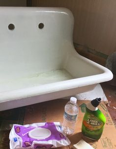 a white bathtub sitting on top of a wooden floor next to bottles and soap