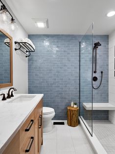 a modern bathroom with blue tile and wood accents on the walls, along with a walk in shower