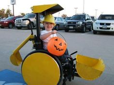 a young boy in a wheel chair with a pumpkin on his head and a yellow helmet