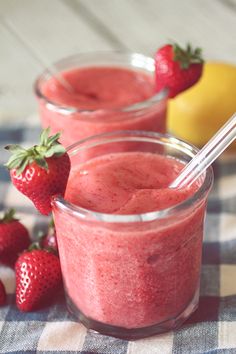 two small cups filled with strawberry smoothie and strawberries