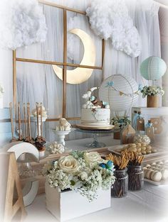 a table topped with cakes and flowers on top of a white table cloth covered in clouds