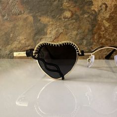 These heart sunglasses are wrapped with black and gold wire.Comes with a cleaning cloth and a pouch to store the sunglasses in. All orders include freebie crystals and stickers. Heart-shaped Glass Sunglasses For Gift, Heart-shaped Glass Sunglasses As Gift, Gradient Lens Glass Sunglasses As Gift, Gradient Glass Sunglasses As A Gift, Black Sunglasses With Tinted Lenses As Gift, Black Sunglasses With Tinted Lenses For Gift, Black Sunglasses With Tinted Lenses, Black Glass Sunglasses For Festival, Black Tinted Sunglasses As A Gift