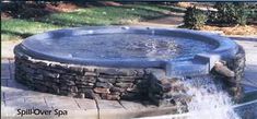 an above ground swimming pool surrounded by stone walls and water spouting from it