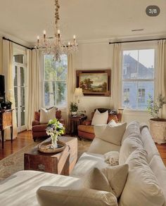 a living room filled with lots of furniture and a chandelier hanging from the ceiling