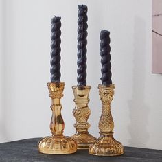 two gold and black candlesticks sitting on top of a table