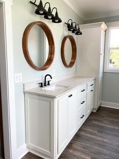 Master bathroom with round wooden mirrors and white vanity Sea Salt Walls, Modern Farmhouse Bathroom Small, Black Light Fixtures, Sw Sea Salt, Wooden Mirrors, Modern Farmhouse Bathroom Ideas, Modern Farmhouse Bathroom Decor, Round Wooden Mirror, Farmhouse Bathroom Design