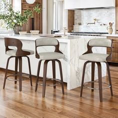 two bar stools sit in front of an island with marble countertops and wooden cabinets