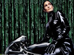 a woman sitting on top of a motorcycle in front of green and black wallpaper