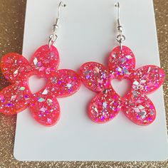 Add a touch of romance to your Valentine's Day attire with our Glitter Pink Flower-  Heart Earrings. These exquisite earrings are crafted from high-quality resin in a flower shape with a heart cutout in the center, making them the perfect statement piece for the season of love.  Our hypoallergenic earrings come with stainless steel posts for easy and comfortable wear, so you can enjoy them all day or night without any discomfort. The stunning glitter finish adds just the right amount of sparkle to your look, making these earrings an ideal gift for yourself or someone special. Whether you're dressing up for a romantic dinner date or adding a little sparkle to your casual outfit, our Glitter Pink Heart Earrings are sure to turn heads and make you feel extra special this Valentine's Day. Don' Sparkle Heart Earrings, Flower Shaped Earrings For Valentine's Day, Flower-shaped Earrings For Valentine's Day, Cute Party Earrings With Flower Shape, Cute Flower Shaped Party Earrings, Pink Flower-shaped Earrings For Valentine's Day, Pink Flower Drop Earrings For Valentine's Day, Pink Heart-shaped Flower Earrings For Gift, Pink Heart-shaped Flower Earrings As Gift