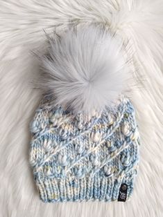 a blue and white knitted hat with a pom - pom on top