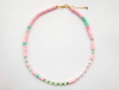 a pink, green and white beaded necklace on a gold plated bracelet chain