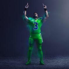 a man in a green football uniform holding his hands up