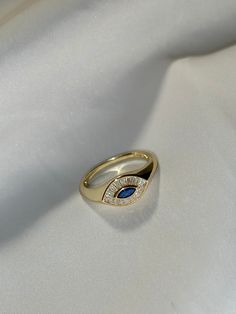 Introducing our stunning Evil Eye Ring, a captivating piece that exudes mystique and elegance. Crafted in luxurious gold, this ring features a unique design resembling a mesmerizing eye. At the center, a striking blue gemstone commands attention, encircled by exquisite clear stones that mimic the intricate details of an iris and delicate eyelashes. The juxtaposition of colors and textures creates a truly enchanting aesthetic. Elevate your style and protect yourself with this alluring Evil Eye Ring -- Material: Solid .925 Sterling Silver / 14k Gold Plated -- Stones: Round cubic zirconia stones -- Color: Silver / Gold -- Ring Sizes: 6, 7, 8, and 9 -- All of our products are handcrafted.   Merchandise images are enlarged to show detail and may not always be exactly as pictured. Due to the nat Nana Ring, Ring Redesign, Enchanting Aesthetic, Evil Eye Ring, Gold And Silver Rings, Eye Ring, Clear Stone, Ring Sizes, Protect Yourself