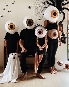 three people sitting on a bench with paper hats over their faces and two ghost heads above them