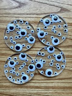 four glass plates with eyes on them sitting on a wooden table next to each other