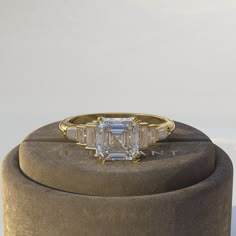 an emerald cut diamond ring on top of a round box