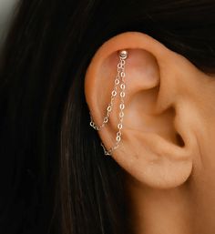 a woman's ear is shown with two chains attached to the side of her ear