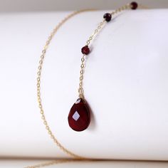 Transform any ensemble with our Teardrop Red Garnet Natural Stones Lariat Necklace! The precisely cut teardrop red garnet gemstone and delicate round red garnet bead on a chain of gold plated 925 sterling silver exude opulence and allure. Featuring a front chain closure, this necklace is effortless to put on and adds a hint of extravagance to your look. Materials: 925 sterling silver, red garnetFinish: gold plateChain length: 18.5 in Jewelry Care: See more information about how to care for your Red Gemstone Drop Necklace For Gift, Elegant Drop Necklace With Gemstone Beads, Elegant Long Drop Gemstone Bead Jewelry, Elegant Ruby Necklace With Delicate Chain, Elegant Ruby Jewelry With Delicate Chain, Elegant Red Jewelry With Delicate Chain, Elegant Red Faceted Necklace, Elegant Gemstone Dangle Drop Necklace, Elegant Red Teardrop Pendant Drop Necklace