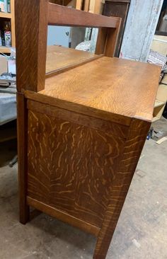 a wooden chair sitting on top of a floor next to a table with a mirror